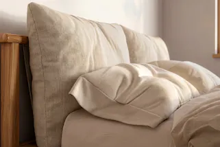 Schlafzimmer mit Massivholzbett und schöner Sommer-Bettwäsche in Creme- und Beigetönen.