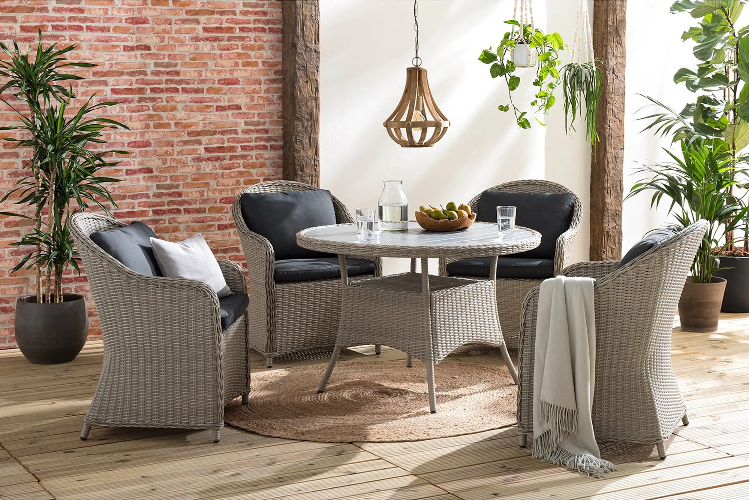 Sitzgruppe mit rundem Tisch aus Polyrattan auf einem ebenfalls runden Juteteppich