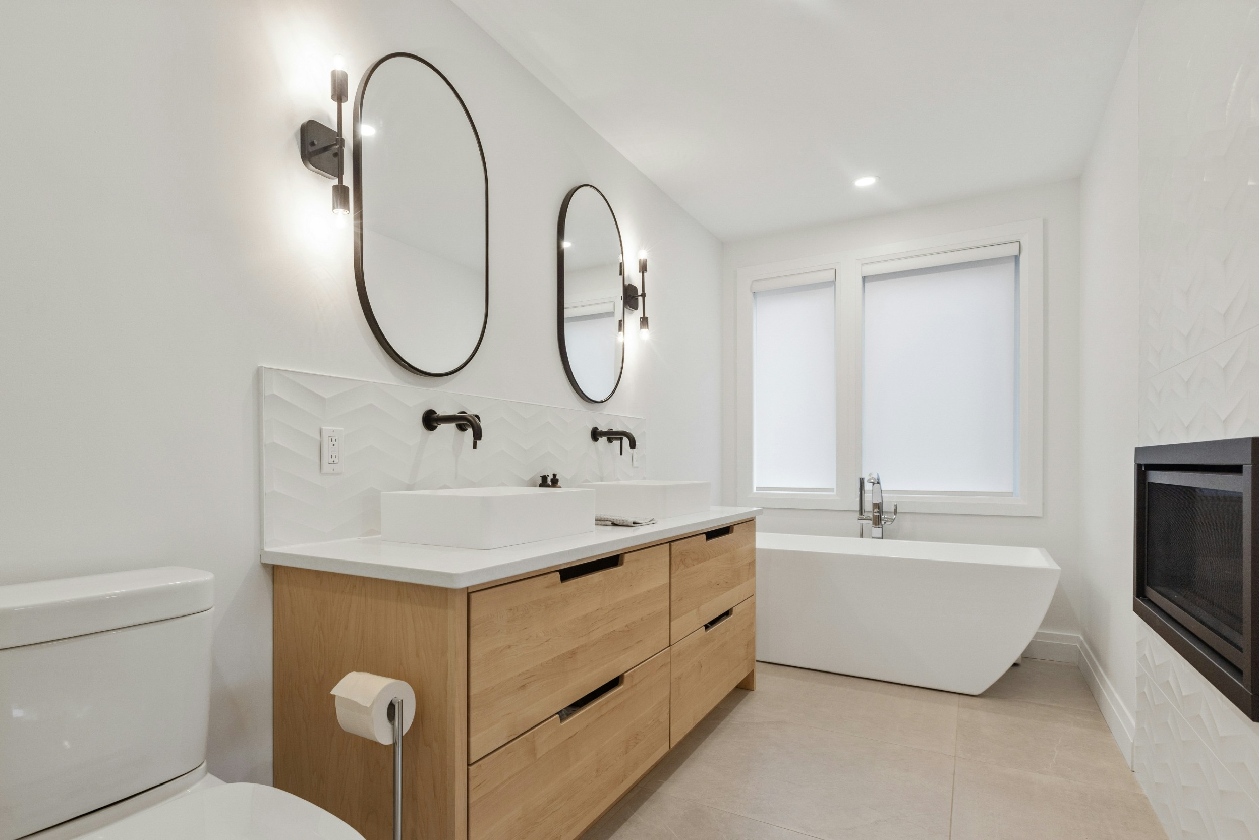 Bad mit Holz-Waschtisch, schwarzen Badspiegeln, WC und freistehender Badewanne