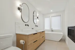 Bad mit Holz-Waschtisch, schwarzen Badspiegeln, WC und freistehender Badewanne