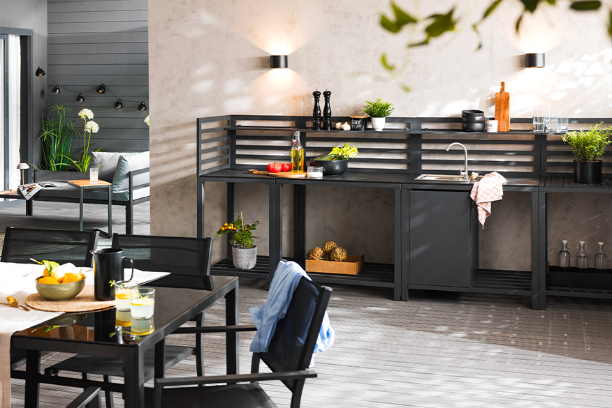 Schwarze Outdoorküche der home24 Exklusivmarke Jardi mit integriertem Spülbecken und praktischen Ablageflächen für Schneidebretter, Geschirr, Gewürze und Co., um den Grillabend direkt im Garten vorzubereiten.