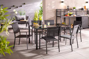 Anthrazitfarbene Gartenessgruppe aus leichten und bequemen Aluminummöbeln, die zum gemütlichen Grillabend im Garten einladen. Im Hintergrund sichtbar: praktische, moderne Outdoorküche in Schwarz.