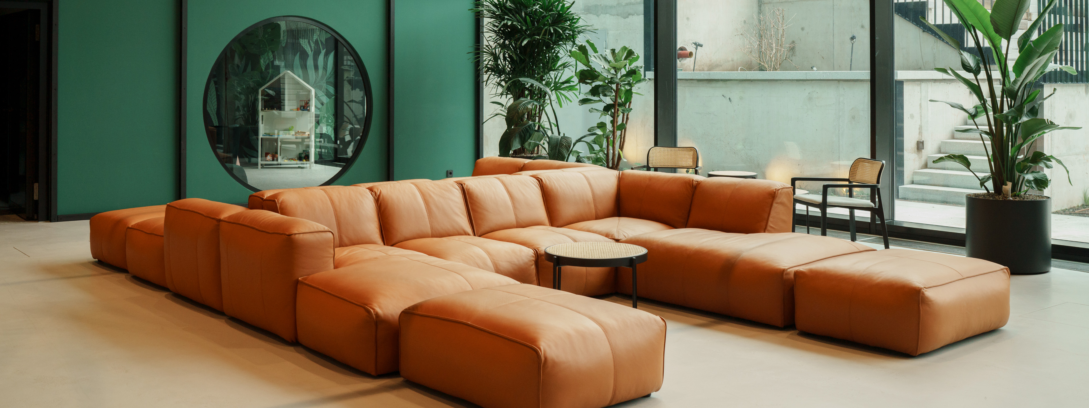 Sofa Hudson von Studio Copenhagen in Cognac auf einem Banner für die home24 Corporate Website.