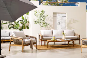 Outdoorlounge Nevis aus Teakholz und Rope Design von der home24 Exklusivmarke Jardi mit vielen Pflanzen, einem natürlichen Juteteppich, hellem Keramikgeschirr sowie weiteren Accessoires.