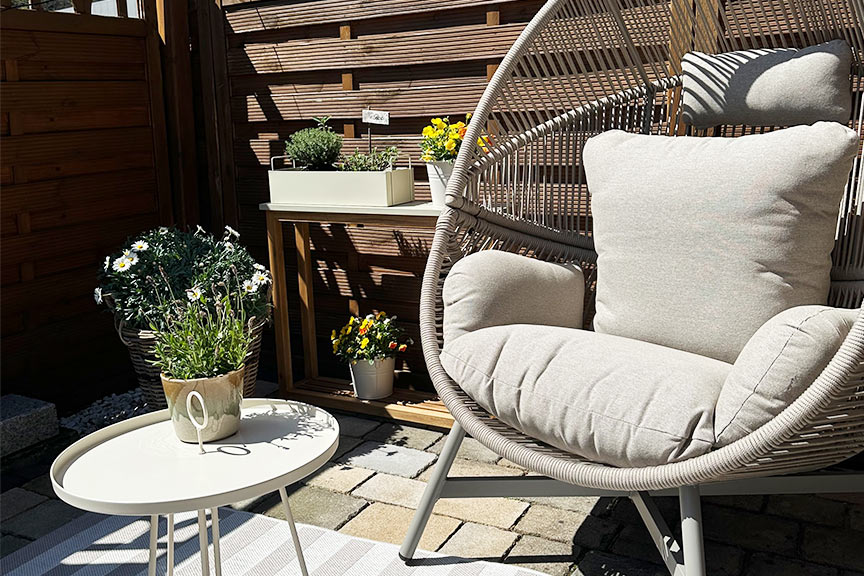 Grauer Gartensessel Lovon mit farblich passendem Beistelltisch und Outdoorteppich