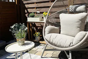 Grauer Gartensessel Lovon mit farblich passendem Beistelltisch und Outdoorteppich