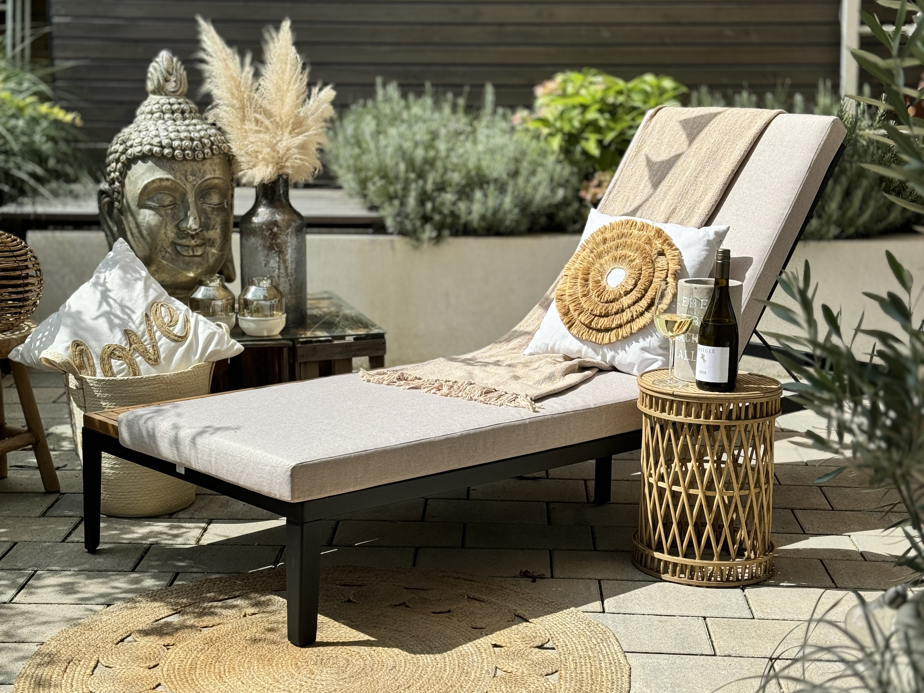 Gartenliege auf sonniger Terrasse mit Boho-Deko gestylt