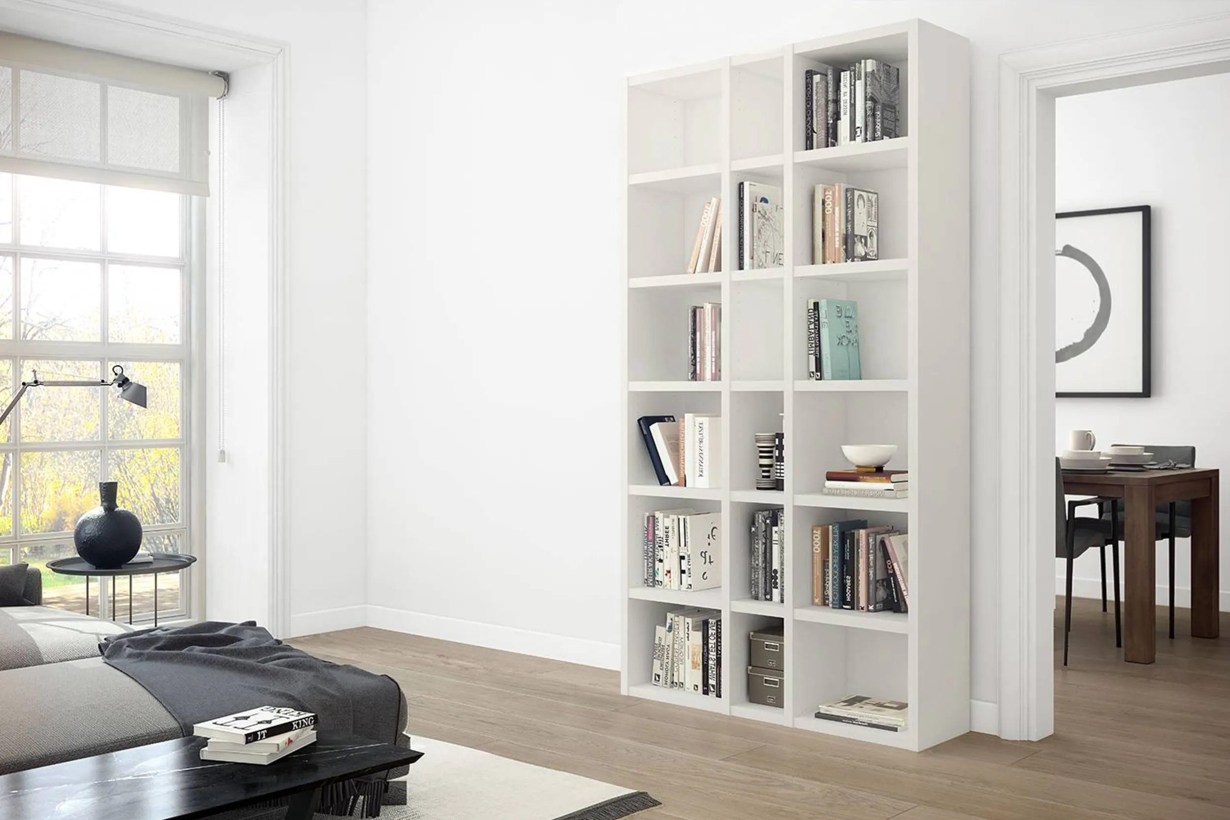 Hohes, weißes Regal mit Büchern in einem hellen Wohnzimmer mit Holzfußboden