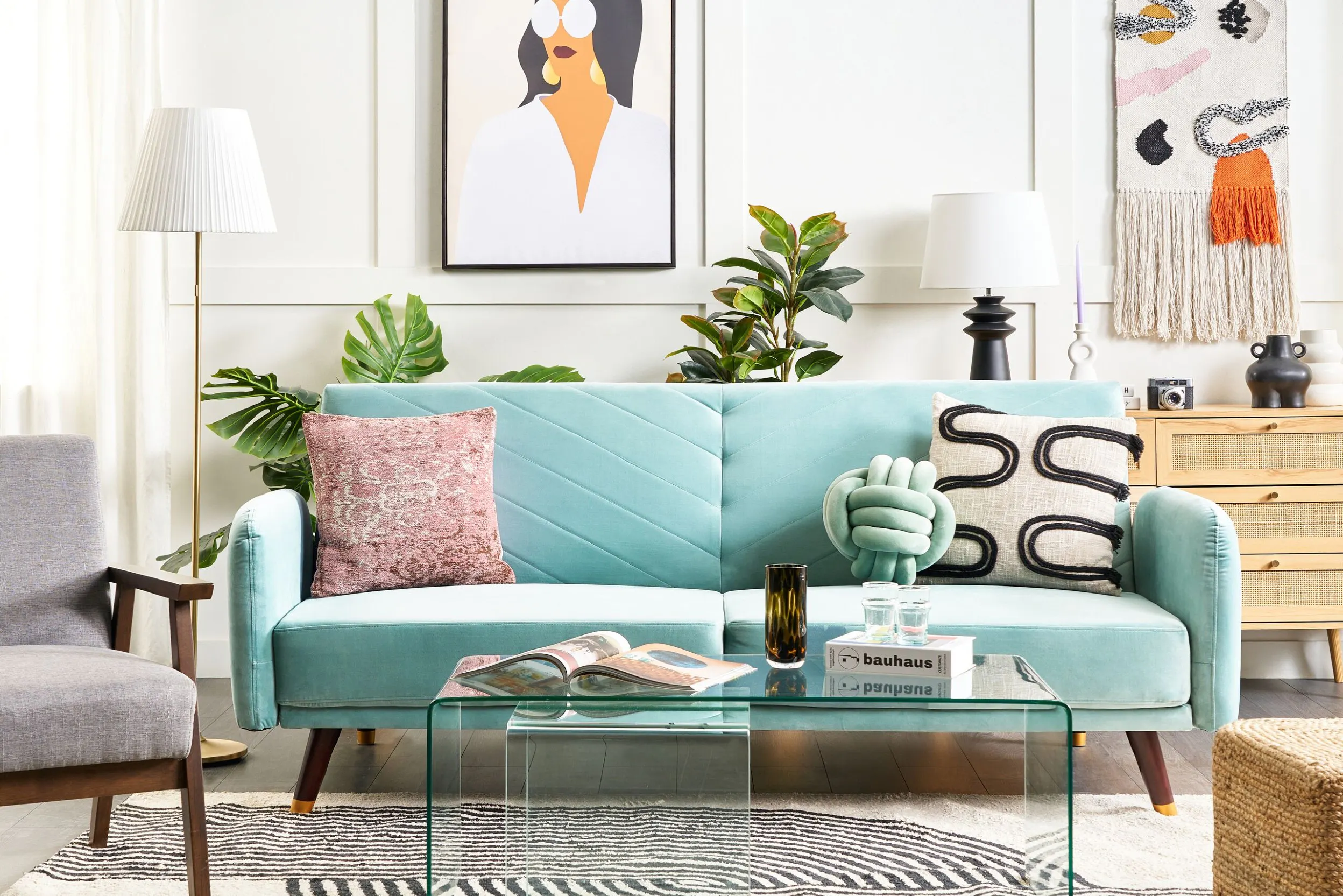 Ein modernes Wohnzimmer zeigt ein hellblaues Sofa mit rosa und weißen Kissen