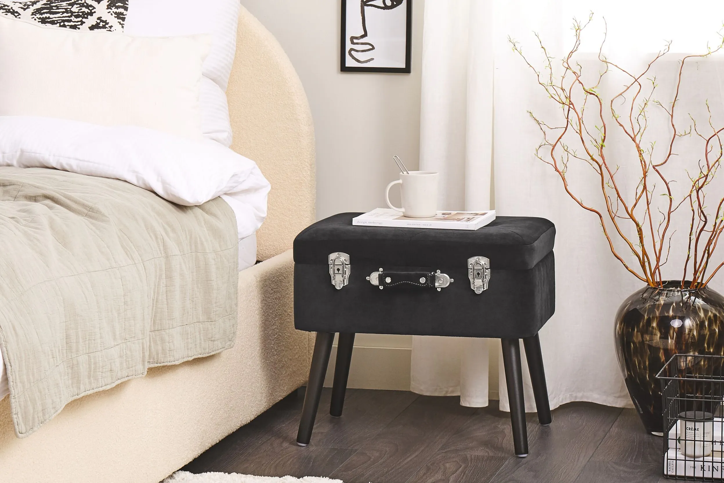 Kleiner schwarzer Samthocker mit silbernen Verschlüssen neben einem Bett