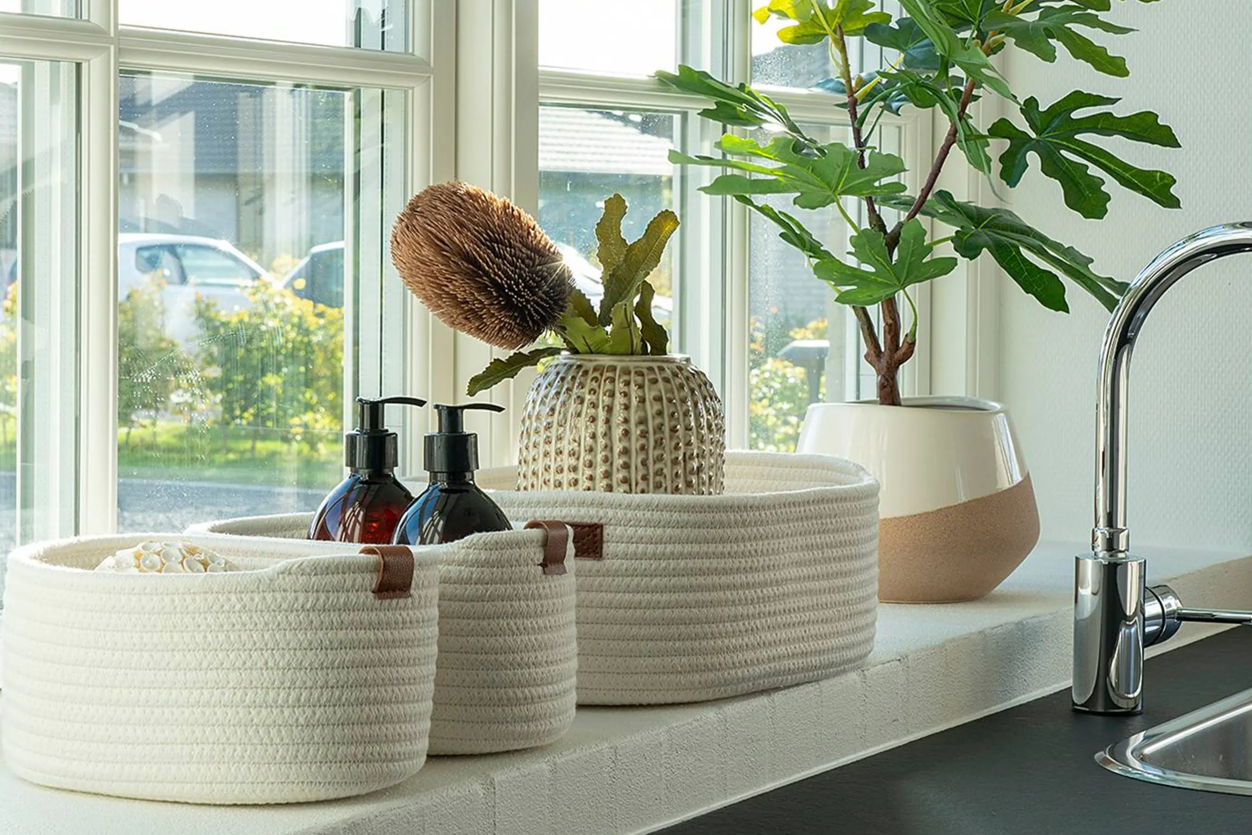 Fensterbank mit einheitlichen Körben und Grünpflanze