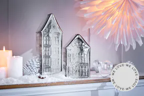 Silberne Dekohäuschen zusammen mit weiterer Weihnachtsdeko in Silber und Weiß