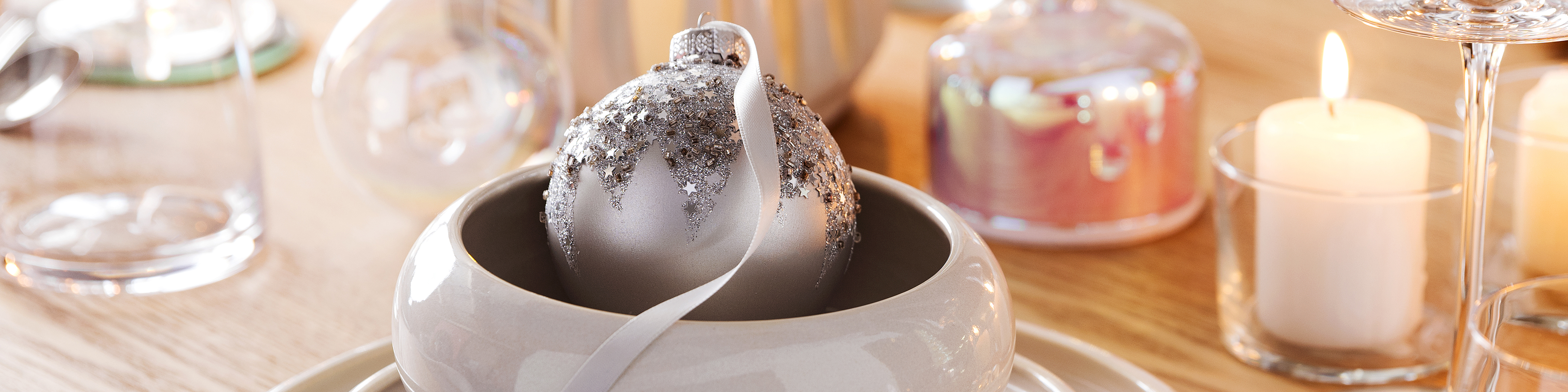 Silberne Christbaumkugel als Deko auf dem gedeckten Weihnachtstisch