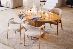 Esszimmer im Skandi-Stil mit einem ovalen Esstisch aus hellem Eichenholz, den dazu passenden Armlehnenstühlen mit grauem Polsterstoff sowie weihnachtlicher Deko von BUTLERS.
