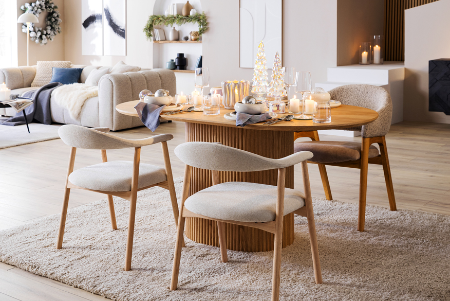 Stilvoller Ess- und Wohnbereich mit Skandi-Möbeln in warmen Holztönen, schwarzen Statement-Möbeln sowie silber-blauer Weihnachtsdeko von BUTLERS.