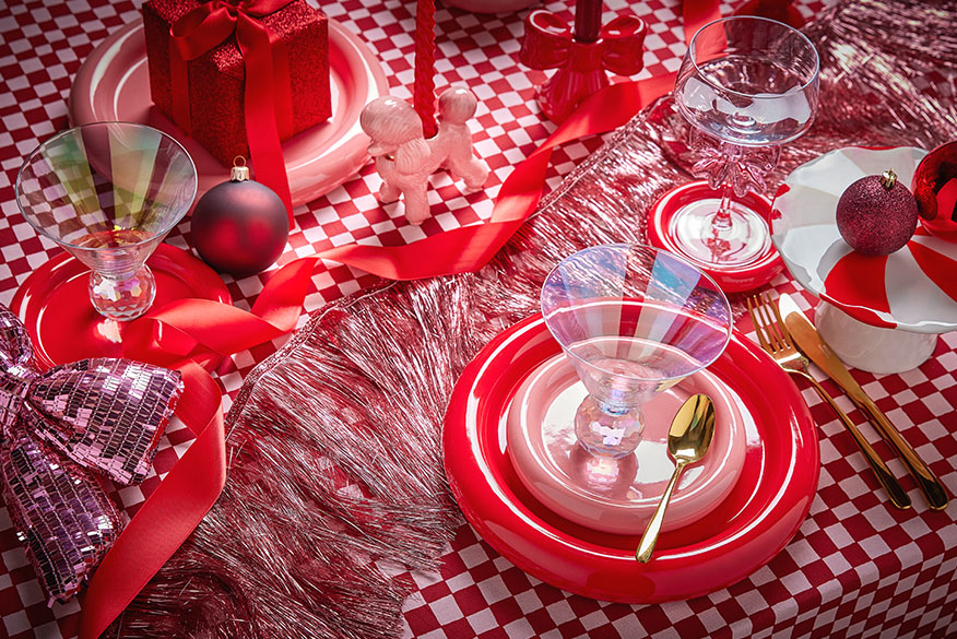 Gedeckter weihnachtlicher Tisch mit Geschirr in rot und pink und karierter Tischdecke