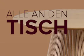 Runder Holztisch mit dem home24 Kampagnenslogan: Alle an den Tisch