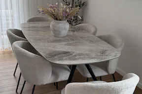 Hellgraue Polsterstühle elegant kombiniert mit hellgrauem Marmortisch.