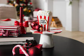 Verspielte Deko wie ein Präsentierteller im rot-weißen Bonbon-Design, ein Kerzenständer in Schleifenform und eine Vase im Look einer Popcorntüte.
