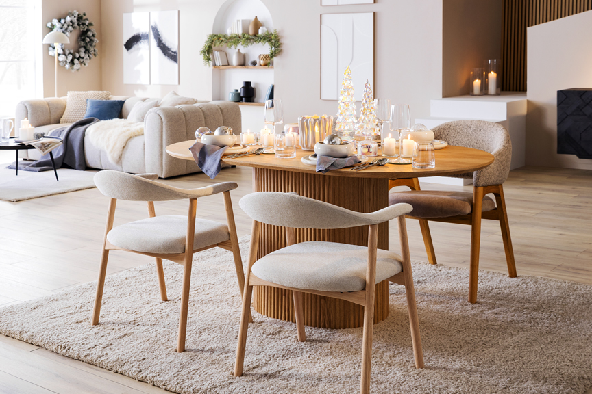 Stilvoller Ess- und Wohnbereich mit Skandi-Möbeln in warmen Holztönen, schwarzen Statement-Möbeln sowie silber-blauer Weihnachtsdeko von BUTLERS.