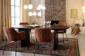 Salle à manger de style art déco moderne avec une table noire, des chaises capitonnées marron, des suspensions dorées en forme de sphère, une enfilade noir ainsi qu’un tapis à motifs.