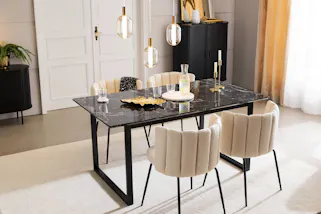 Eleganter Essbereich im Glamourstil mit eleganten Stühlen in beigem Boucléstoff und einem Tisch in Marmoroptik, darauf goldene Schalen, ein Marmortablett und Gläser mit Goldrand, im Hintergrund schwarze Stauraummöbel mit edlen Lamellenfronten.