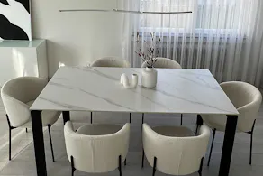Cloud Dancer, couleur Pantone de l'année 2026, mise en scène avec une table au plateau en céramique imitant le marbre, des chaises en bouclé blanc et des vases dans des formes organiques.