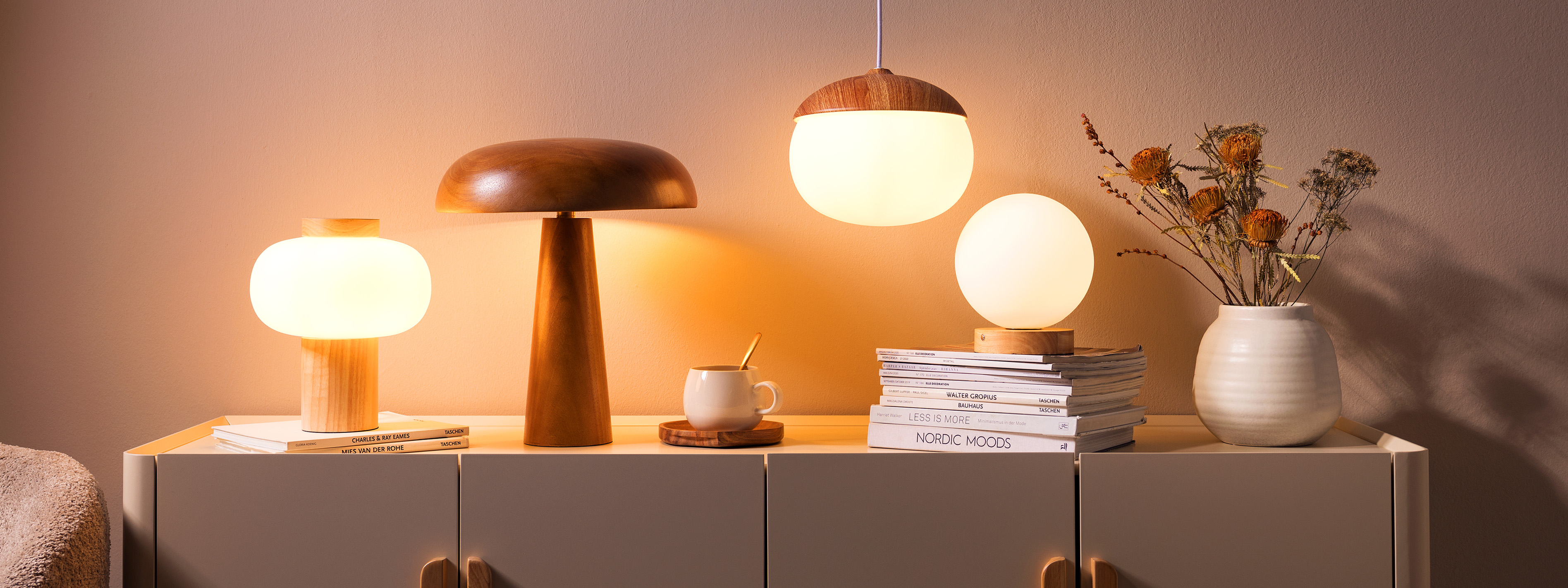 Holzlampen auf einem beigen Sideboard verbreiten warmes Licht, dazu Dekoration für eine gemütliche Wohnatmosphäre.
