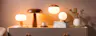 Holzlampen auf einem beigen Sideboard verbreiten warmes Licht, dazu Dekoration für eine gemütliche Wohnatmosphäre.