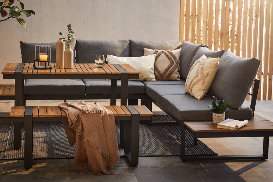 Dining-Loungeset mit Polstern, Lamellenoptik und vielen Kissen; daneben eine weitere Dining-Lounge in einem Garten mit gedecktem Tisch.