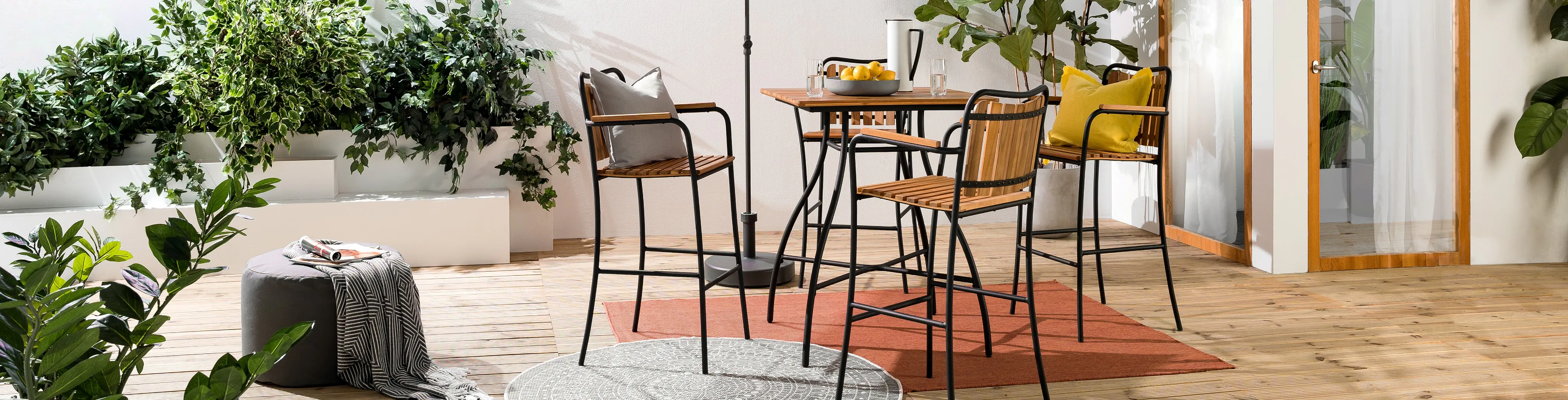 Terrasse mit Barmöbeln und verschiedenen Outdoor-Teppichen