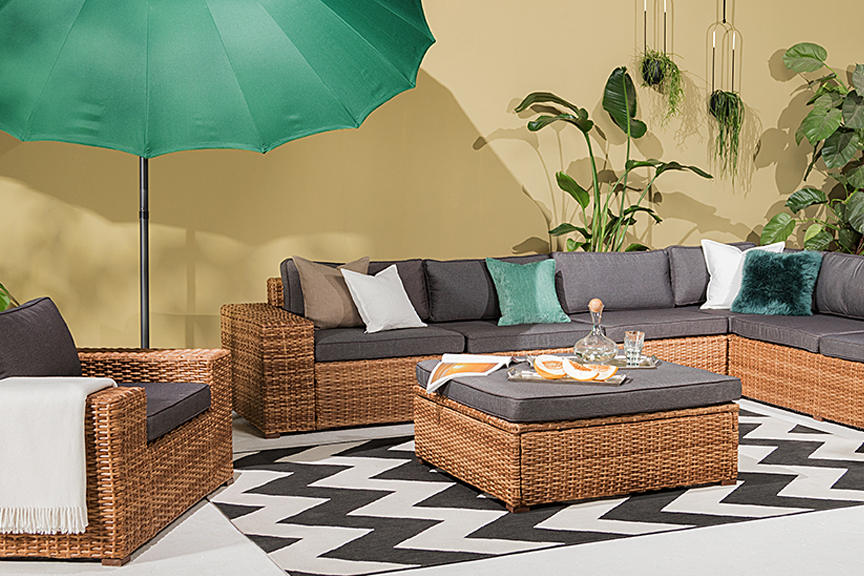XXL-Terrasse mit Loungemöbeln aus Polyrattan, einem grünen Sonnenschirm sowie einem Outdoorteppich mit Zickzack-Muster.