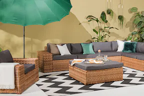 XXL-Terrasse mit Loungemöbeln aus Polyrattan, einem grünen Sonnenschirm sowie einem Outdoorteppich mit Zickzack-Muster.