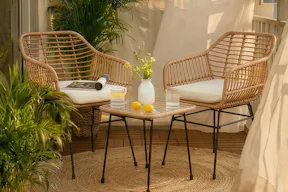 Balkon im beliebten Bali-Look mit einem Möbelset aus Rattan, einem Juteteppich und vielen typischen Accessoires wie geflochtenen Körben, Laternen und hübschen Gläsern.
