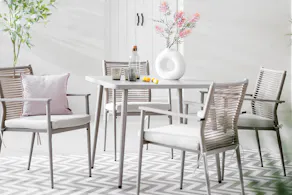 Fauteuils outdoor avec détails en corde sur le dossier et meubles de jardin sur une terrasse claire.