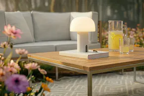 Gartentisch aus Teakholz mit praktischer Outdoor-LED-Lampe, dazu ein Outdoor-Loungesofa.