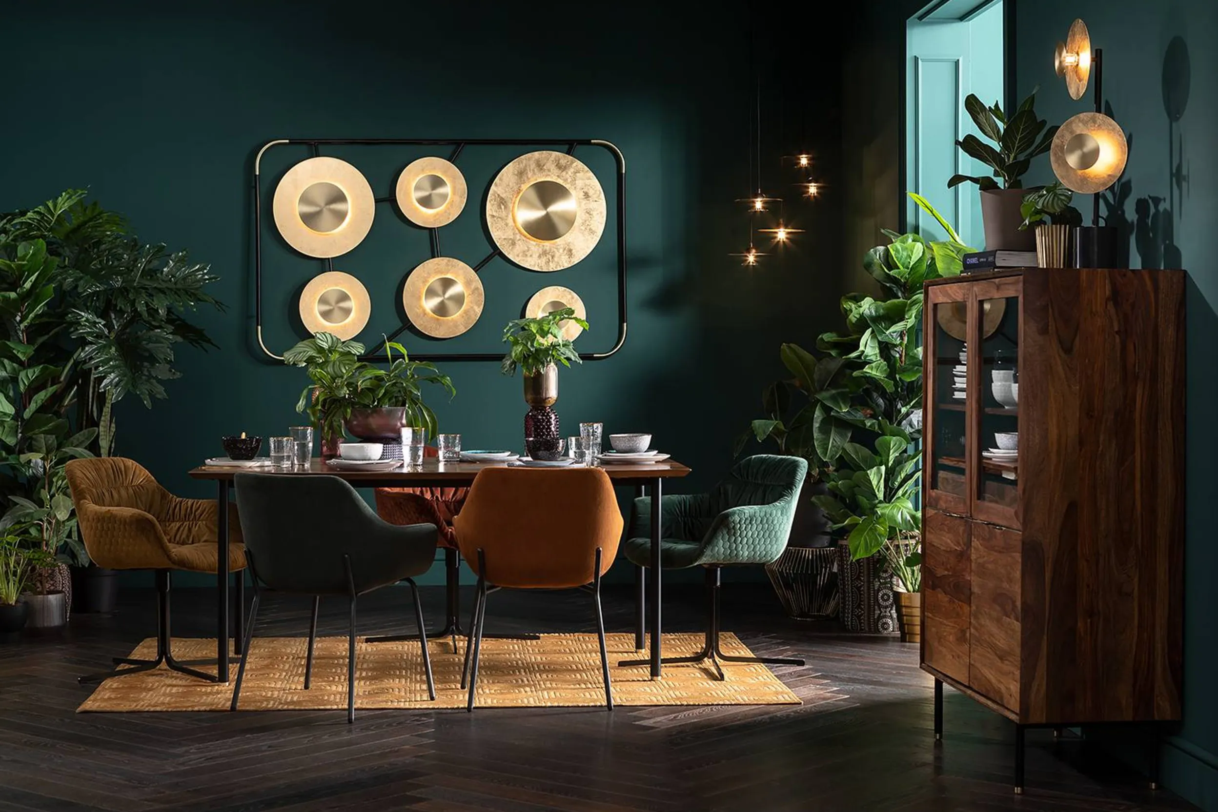 Essbereich mit dunklen grünen Wänden und goldener Statement-Wandlampe