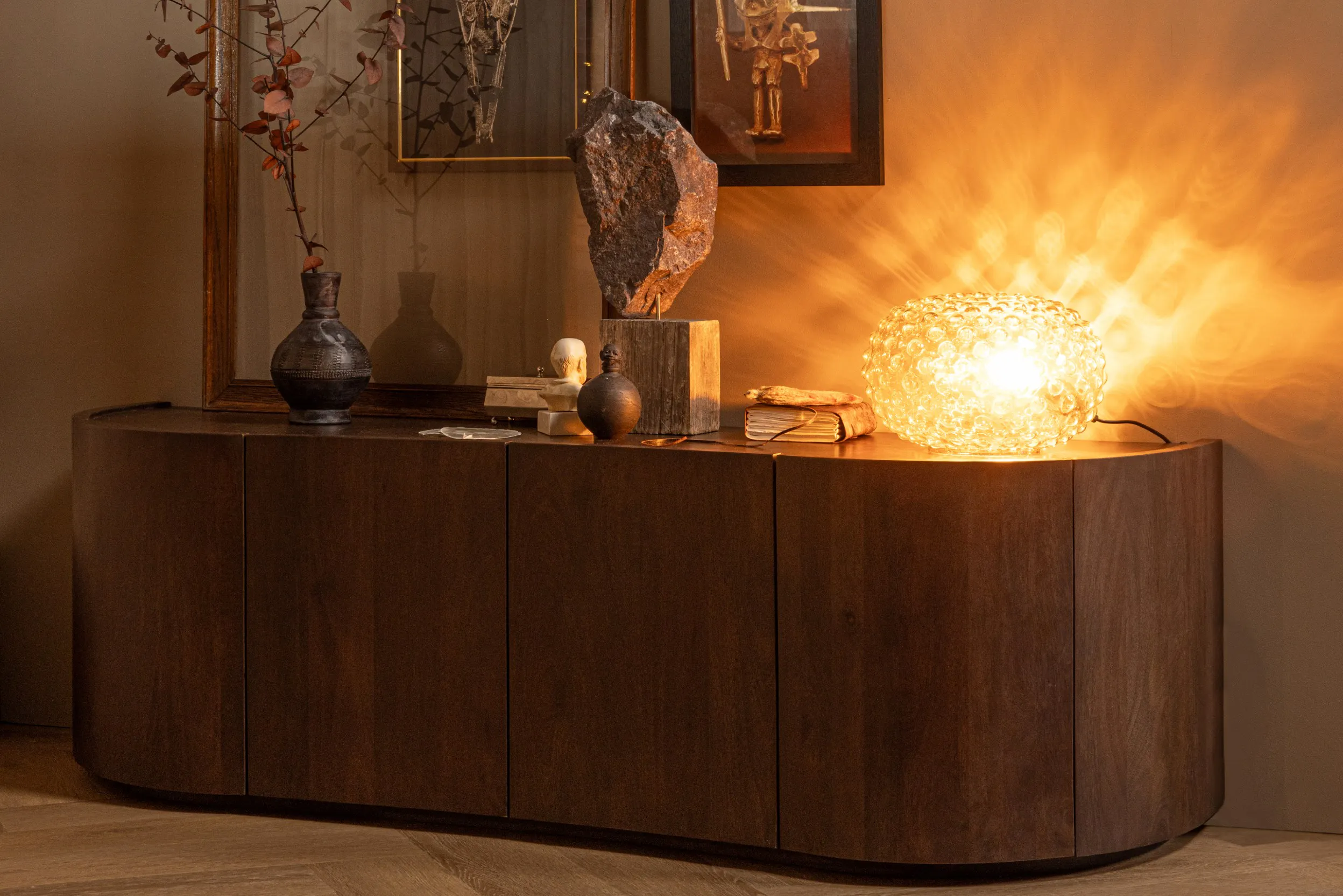 Massives Sideboard aus dunklem Holz mit Deko und Beleuchtung