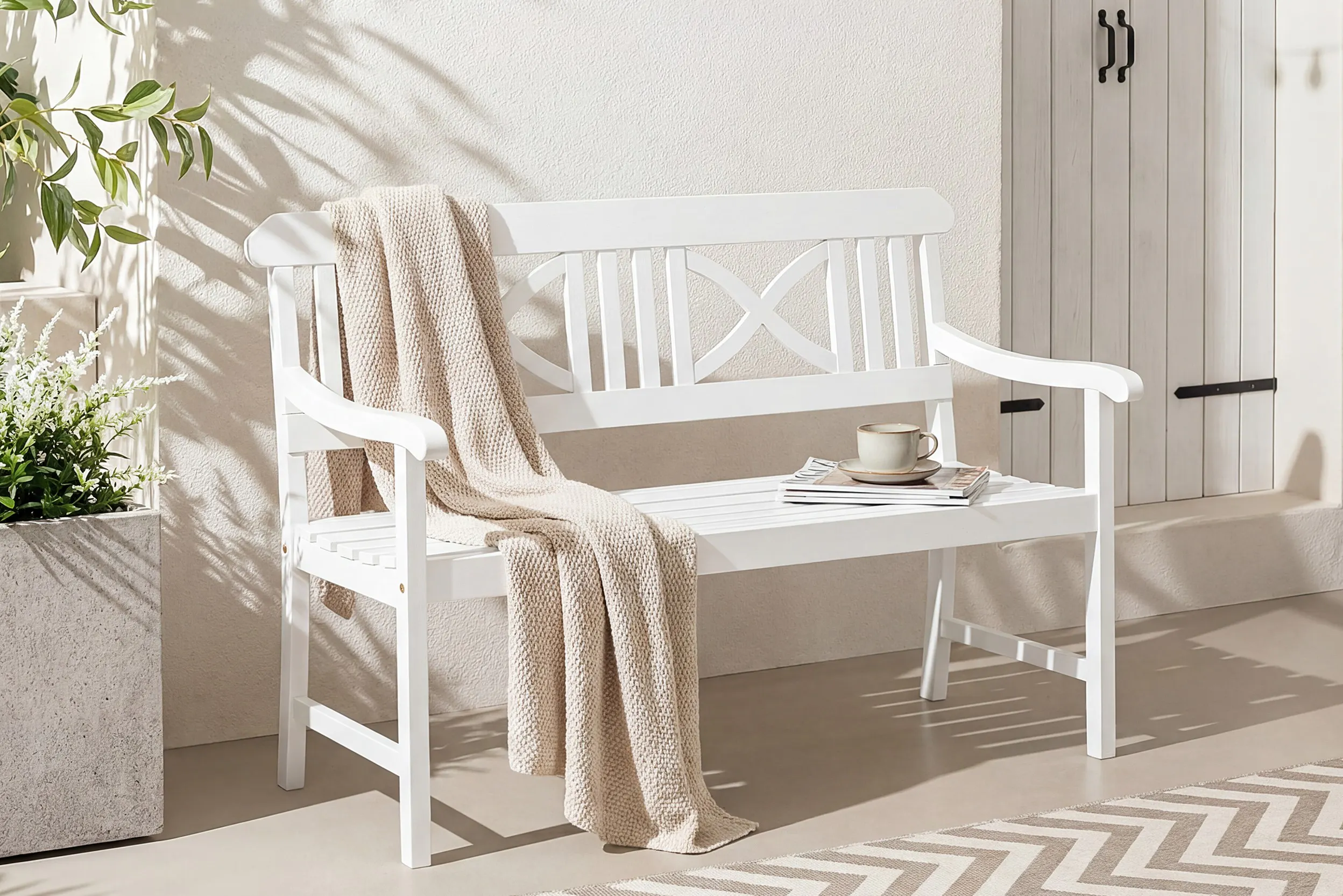 Weiß lackierte Gartenbank mit Tasse und Kuscheldecke