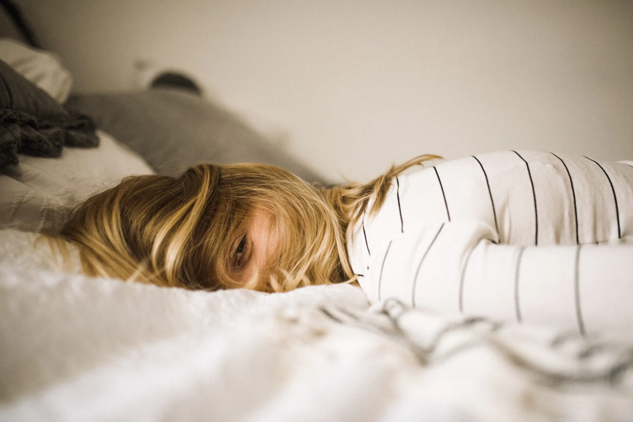 Frau in Bauchlage auf dem Bett mit zufriedenem Gesichtsausdruck