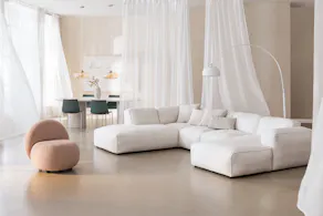 Espace salon et salle à manger de la couleur Pantone Clooud Dancer, avec de légers rideaux beiges et des meubles blancs