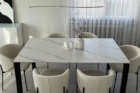 Pantone-Trendfarbe Cloud Dancer gestylt mit einem Keramiktisch in Marmoroptik und weißen Boucléstühlen, dazu Vasen in organischen Formen.