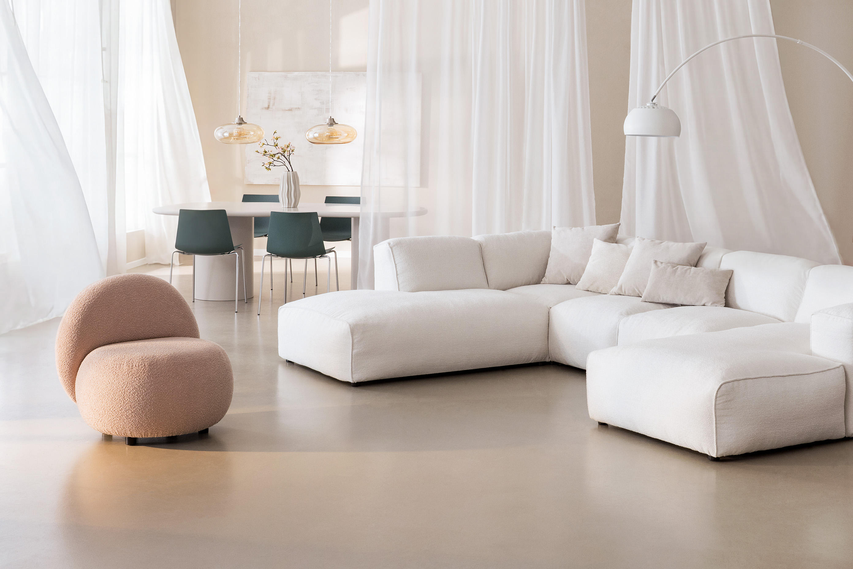 Espace ouvert salon et salle à manger dans des tons clairs inspirés de la couleur Pantone Cloud Dancer, avec des rideaux lumineux et des meubles beiges et blancs.
