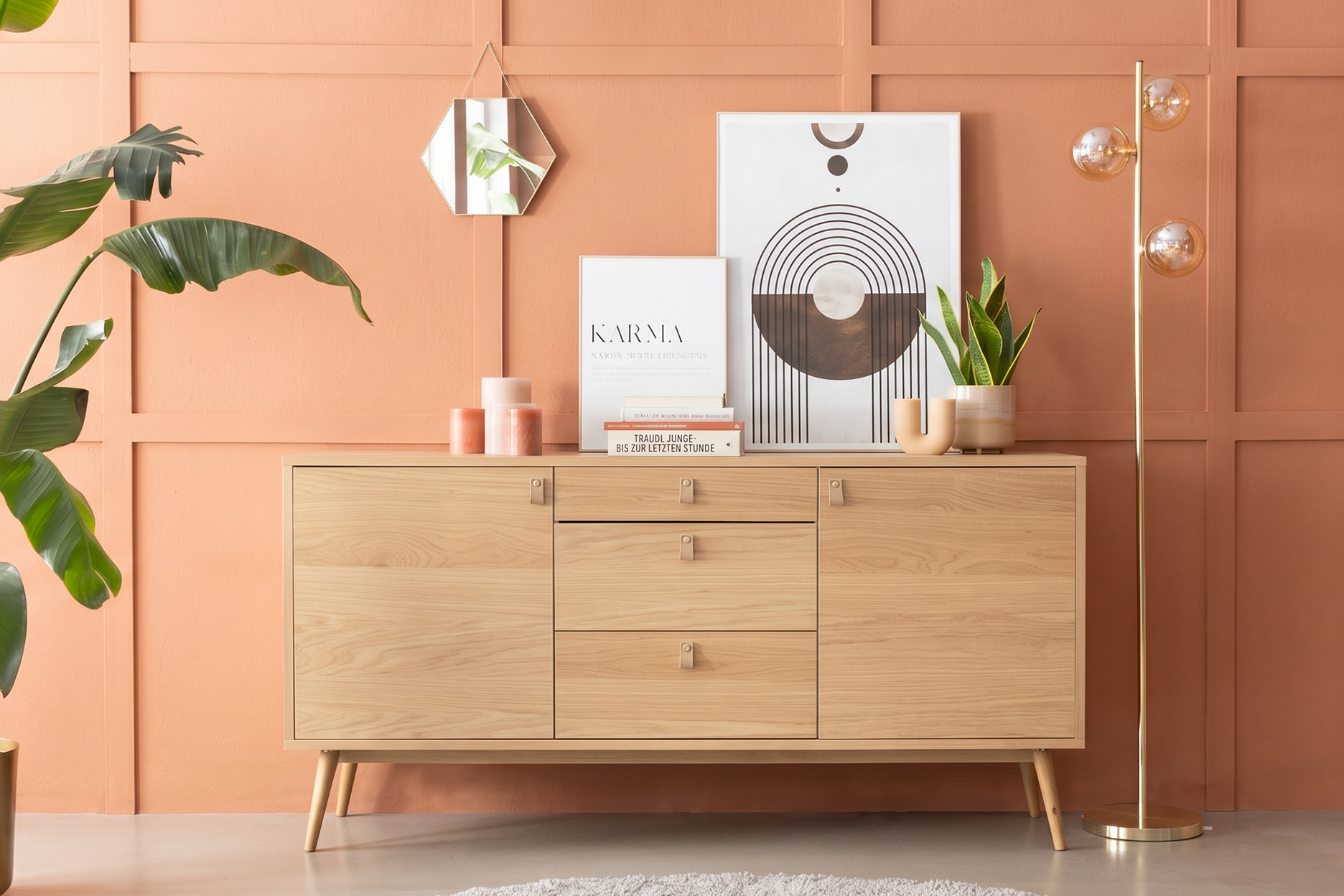 Verspielt dekoriertes Sideboard aus hellem Eichenholzfurnier vor einer orangen Akzentwand.