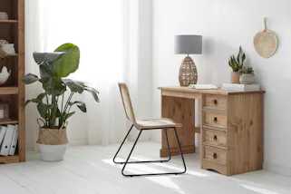 Natürliche Arbeitsumgebung mit Holzschreibtisch, Holzregal und Rattanstuhl.