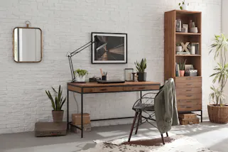 Work-Area mit einer weiß gestrichenen Backsteinwand und authentischem Schreibtisch sowie Standregal im Industrial-Stil.