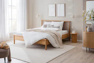Schlafzimmer im Naturstil mit einem Massivholzbett und wohnlichen Textilien.