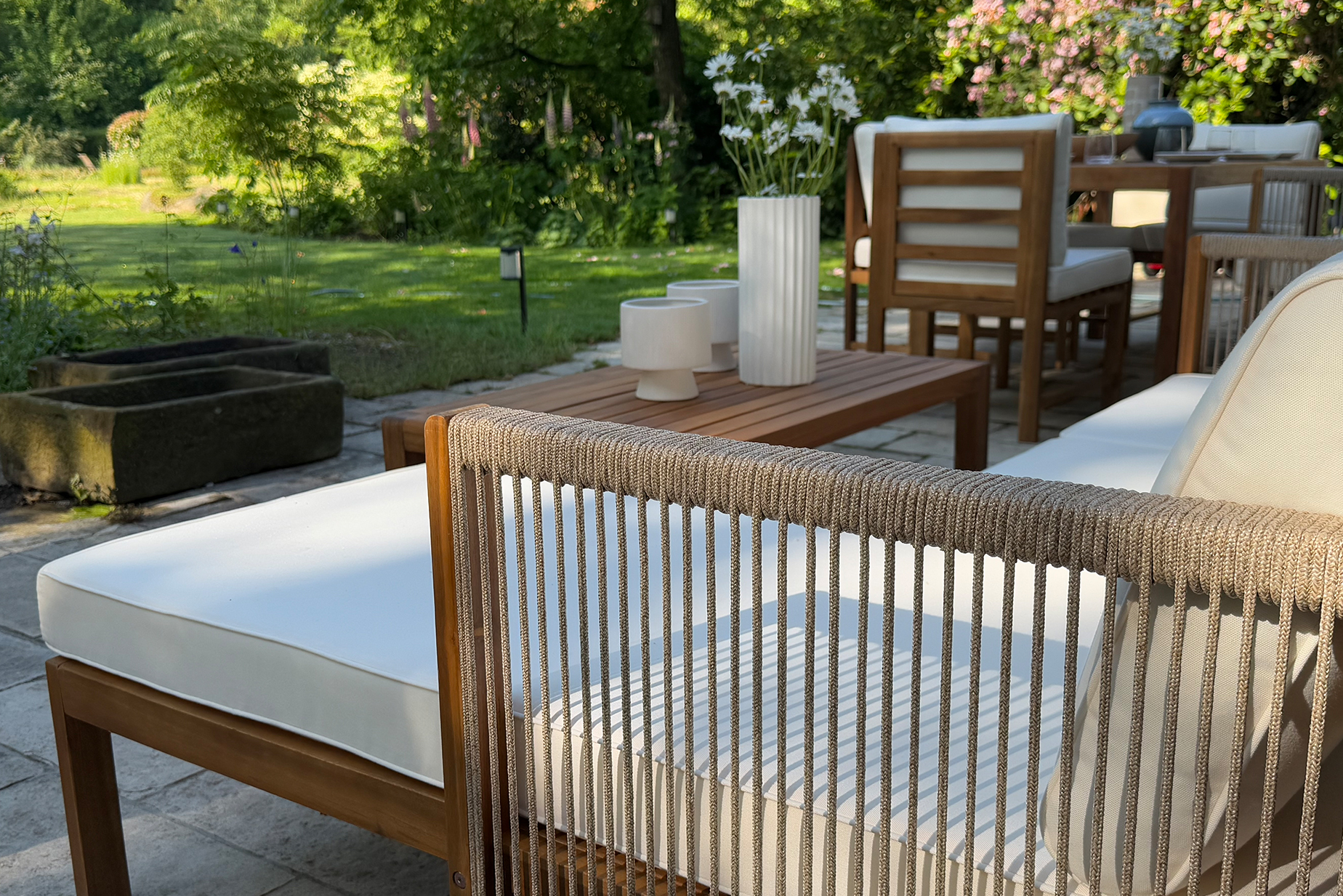 Garten-Loungeecke aus hellem Akazienholz mit hellen Polstern.