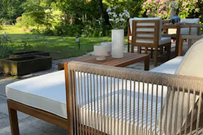 Garten-Loungeecke aus hellem Akazienholz mit hellen Polstern.
