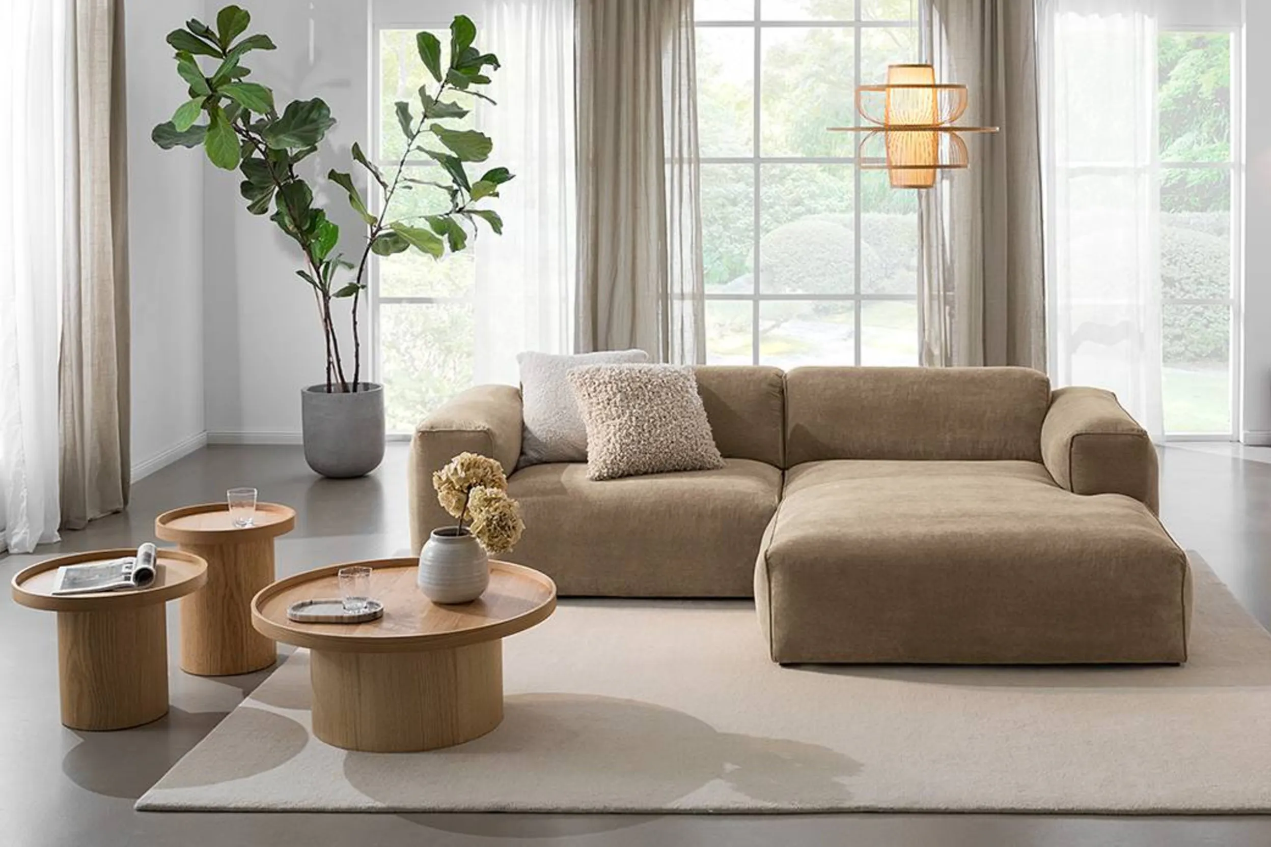 Wohnzimmer mit beigem Ecksofa, hellem Teppich und drei Holztischchen